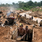 Illegal mining in Ghana showing miners working near polluted river caused by galamsey