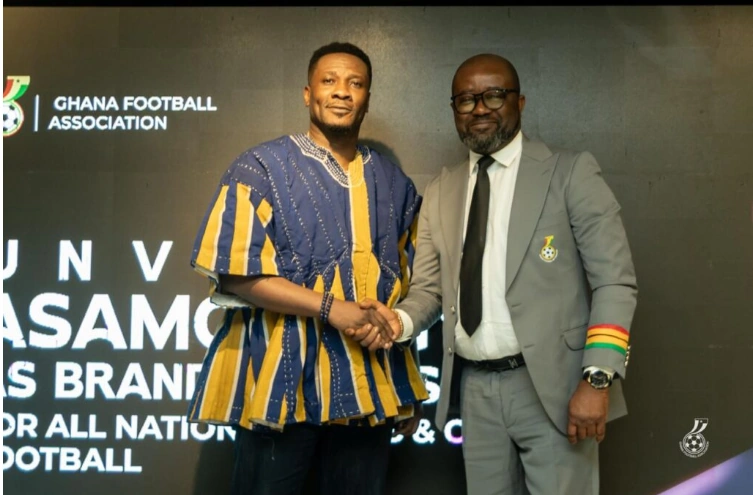 Asamoah Gyan shaking hands with Kurt Okraku at a formal event associated with the Ghana Football Association.