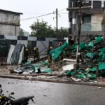 Emergency responders inspect the site of a building collapse as debris covers a rain-soaked street in Accra, Ghana.