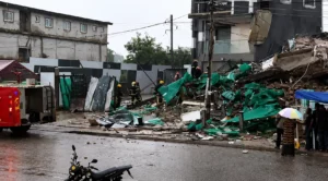 Emergency responders inspect the site of a building collapse as debris covers a rain-soaked street in Accra, Ghana.