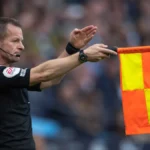 Assistant referee signals an offside decision during a football match.