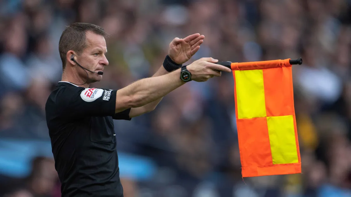 Assistant referee signals an offside decision during a football match.