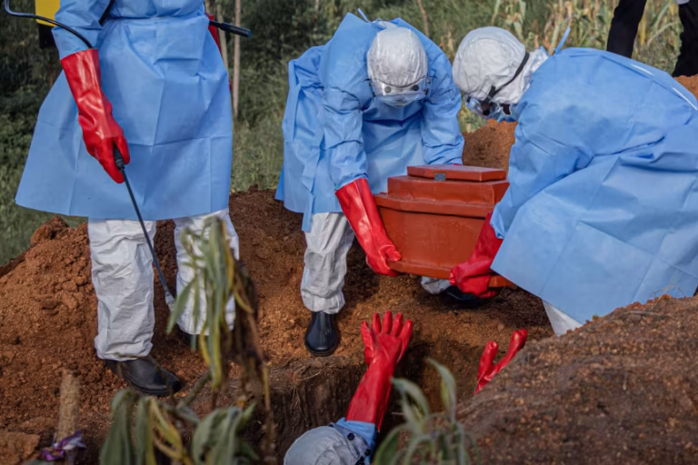 Ebola response worker disinfecting grave during safe burial in DR Congo